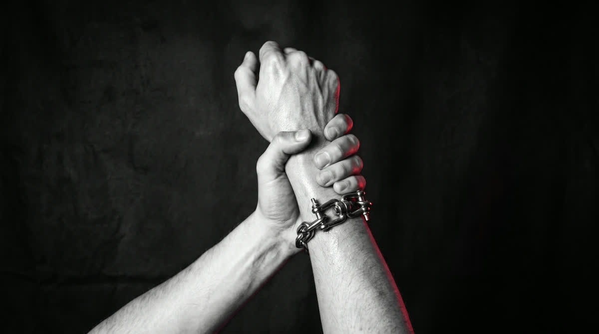 KI-generiertes Motiv: Zwei ineinandergreifende Hände mit Kettenarmband, rotes Licht von der Seite